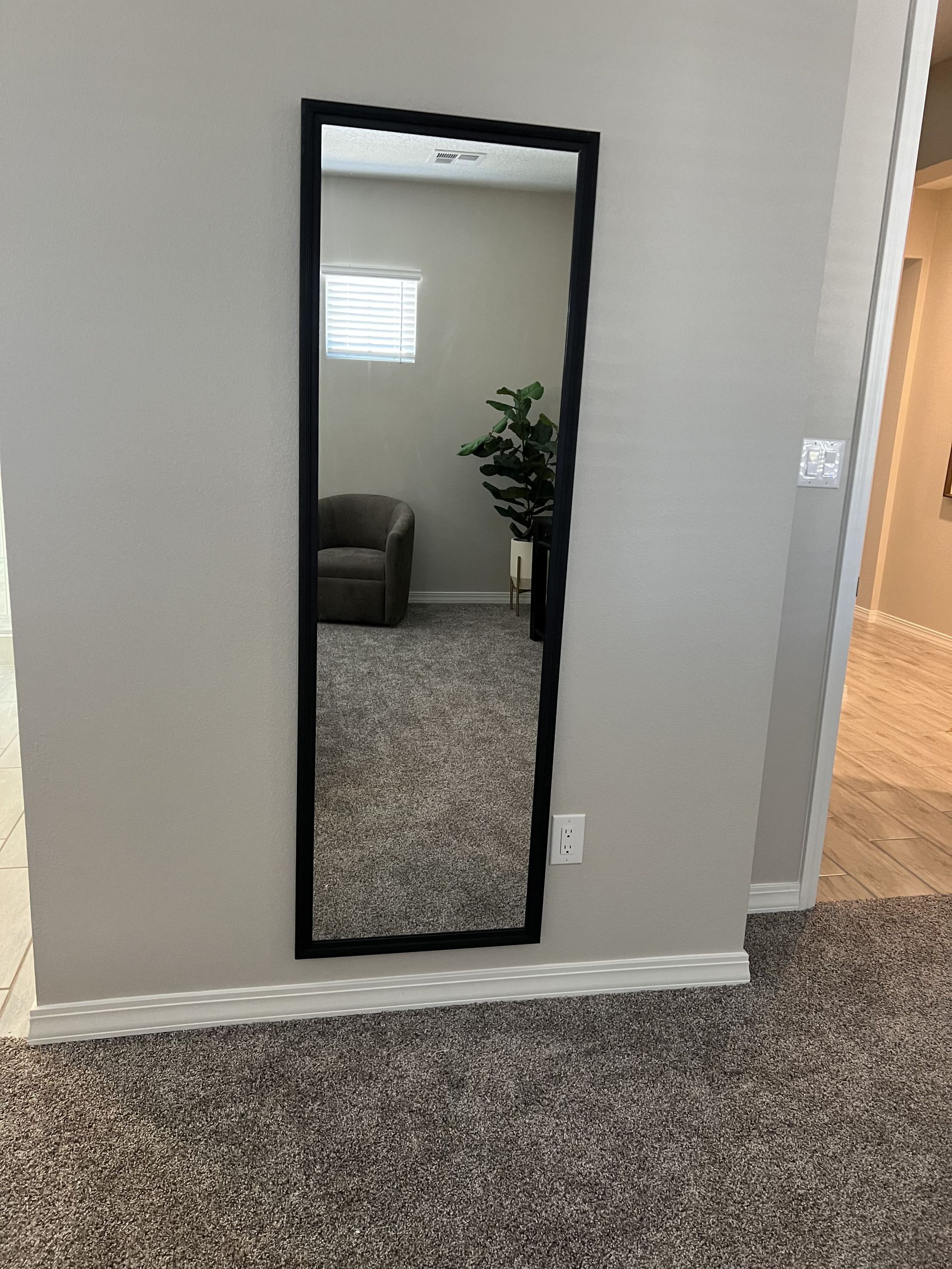 A full length mirror is hanging on a wall in a room.