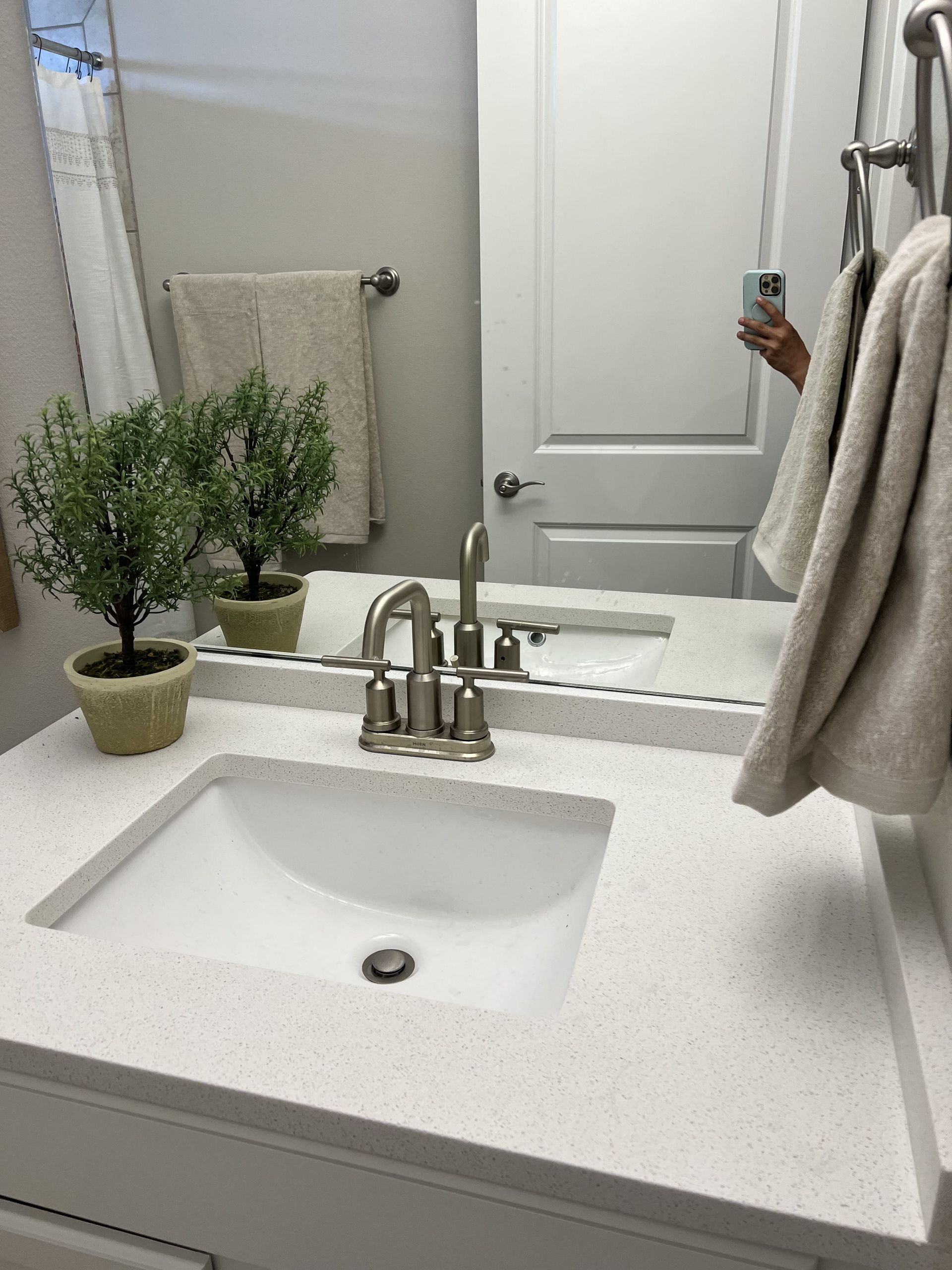 A bathroom sink with a mirror and a person taking a picture of themselves.