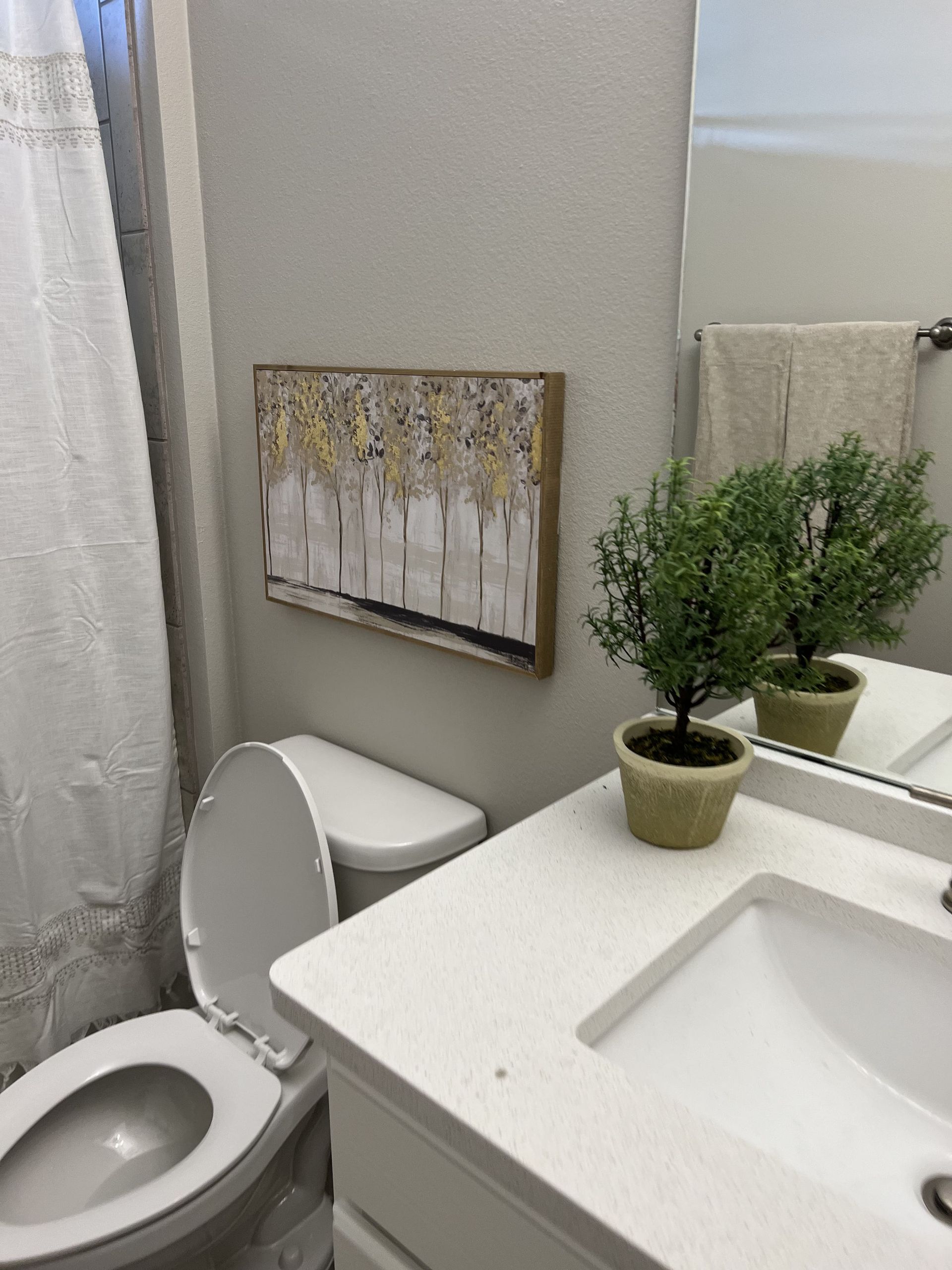A bathroom with a toilet a sink and a painting on the wall