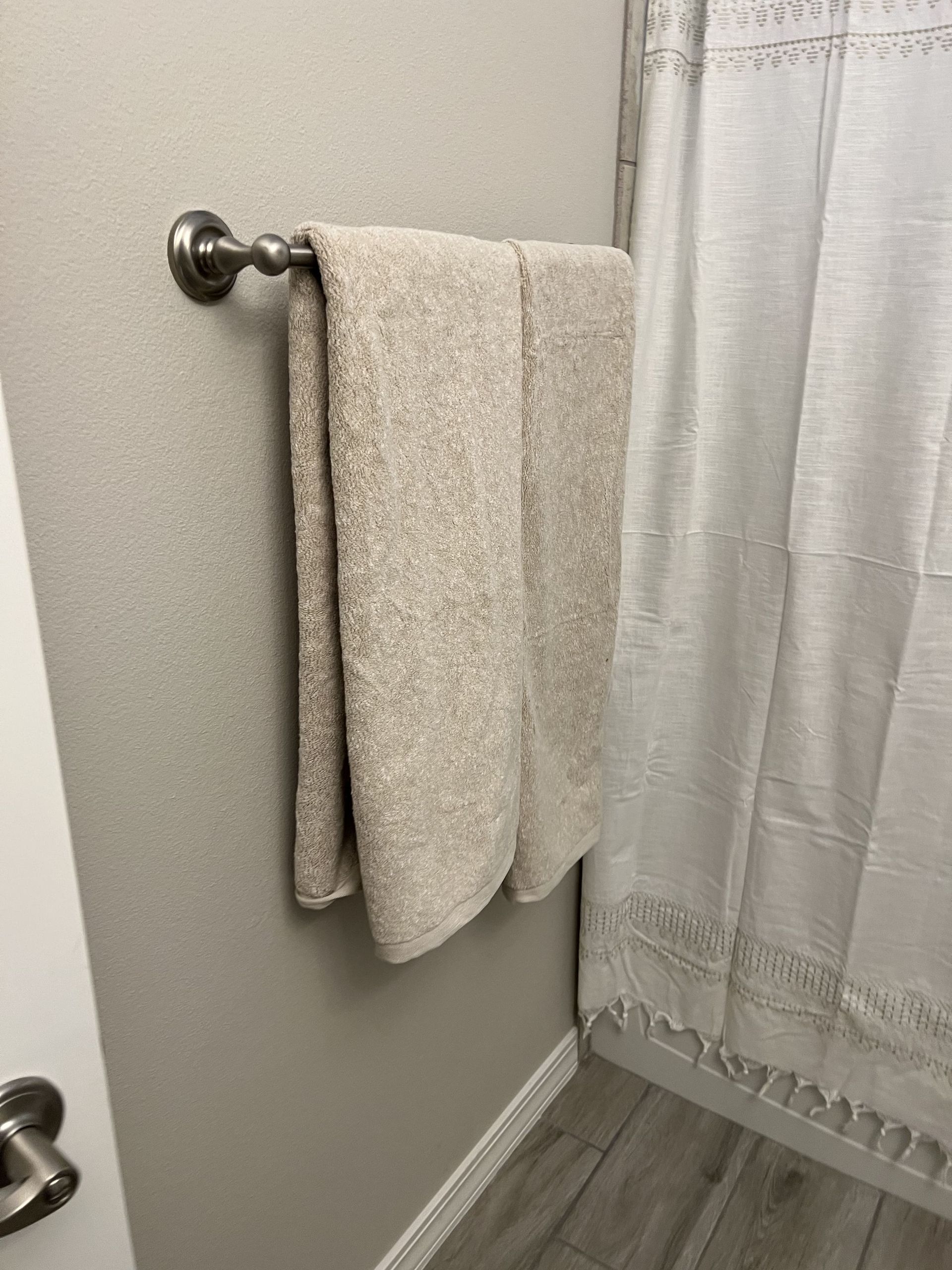 Two towels are hanging on a towel rack in a bathroom next to a shower curtain.