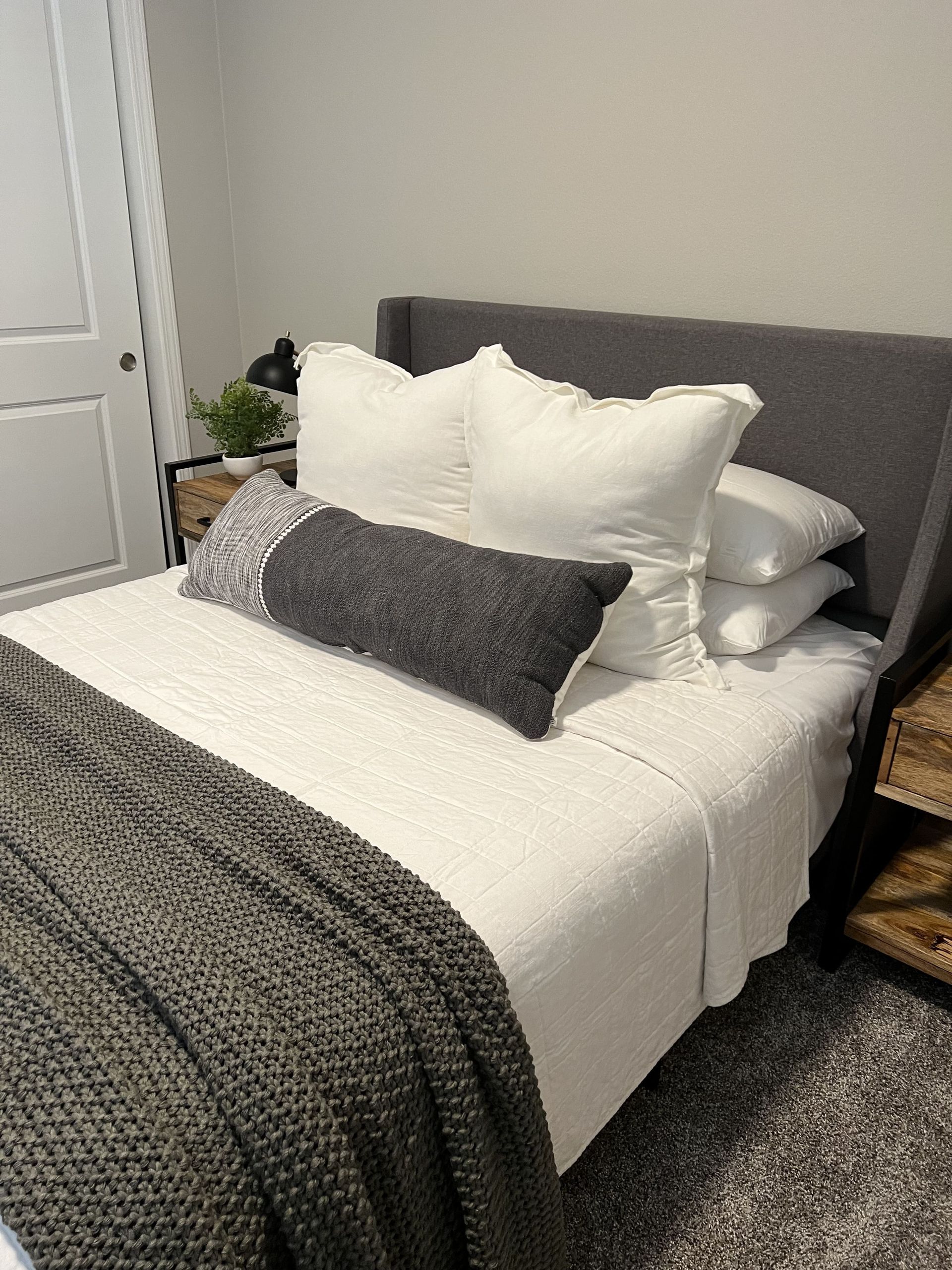 A bed with white sheets and pillows in a bedroom.