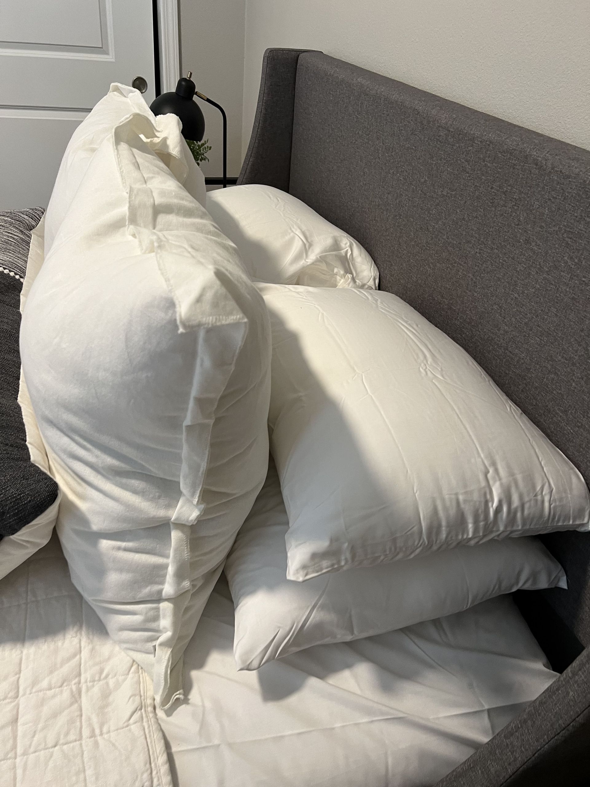 A bed with a lot of white pillows on it.