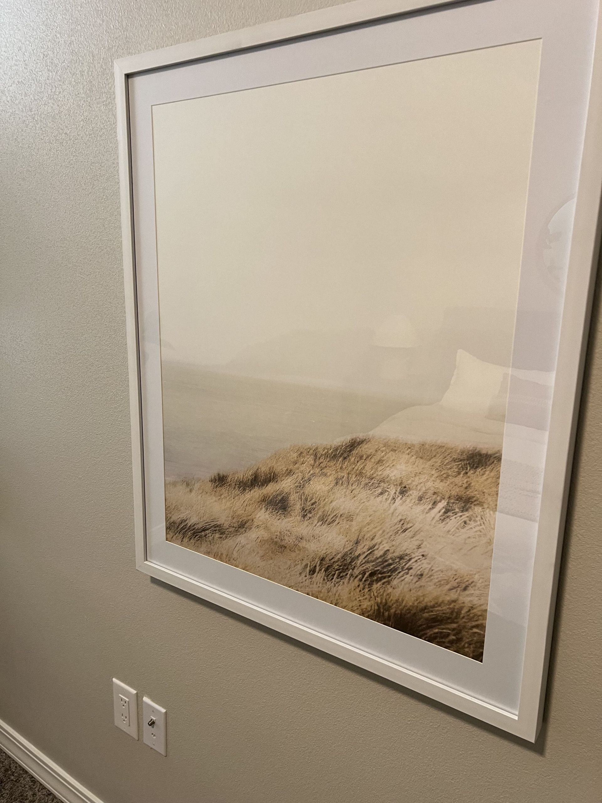 A framed picture of a beach scene is hanging on a wall.