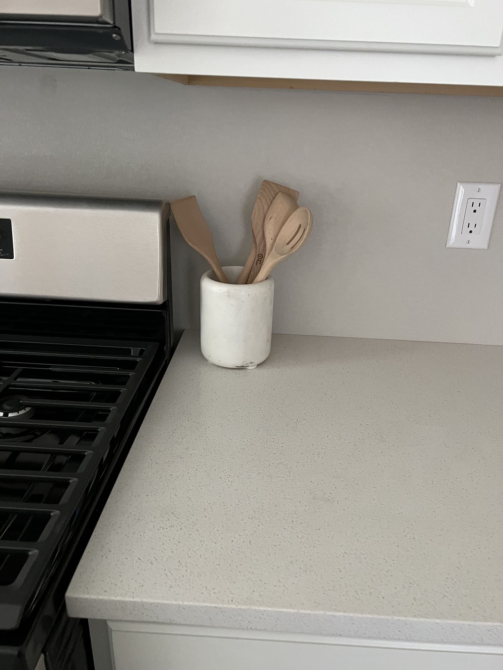 A kitchen counter with a pot of wooden utensils on it.