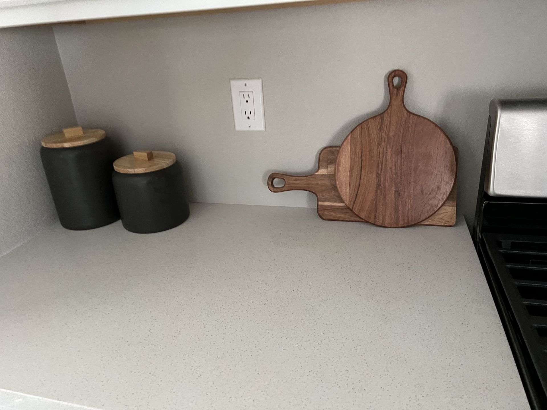 A kitchen counter with a cutting board and two jars on it.