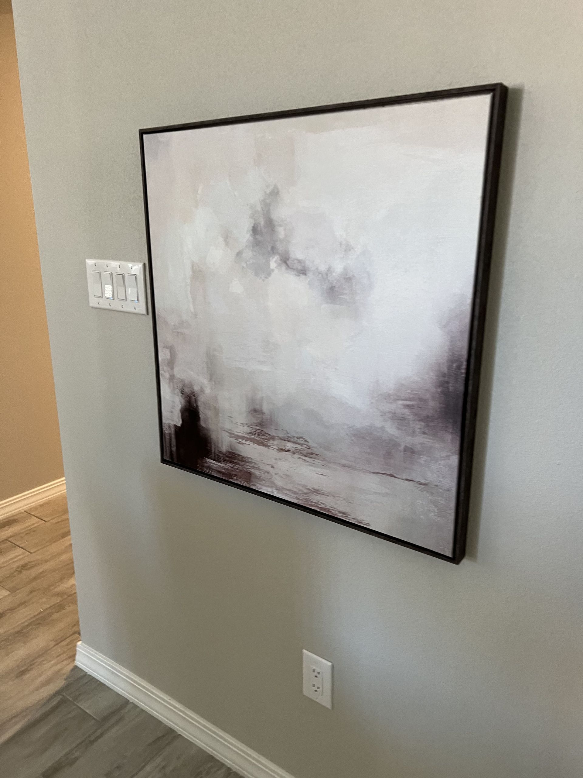 A painting is hanging on a wall in a room.