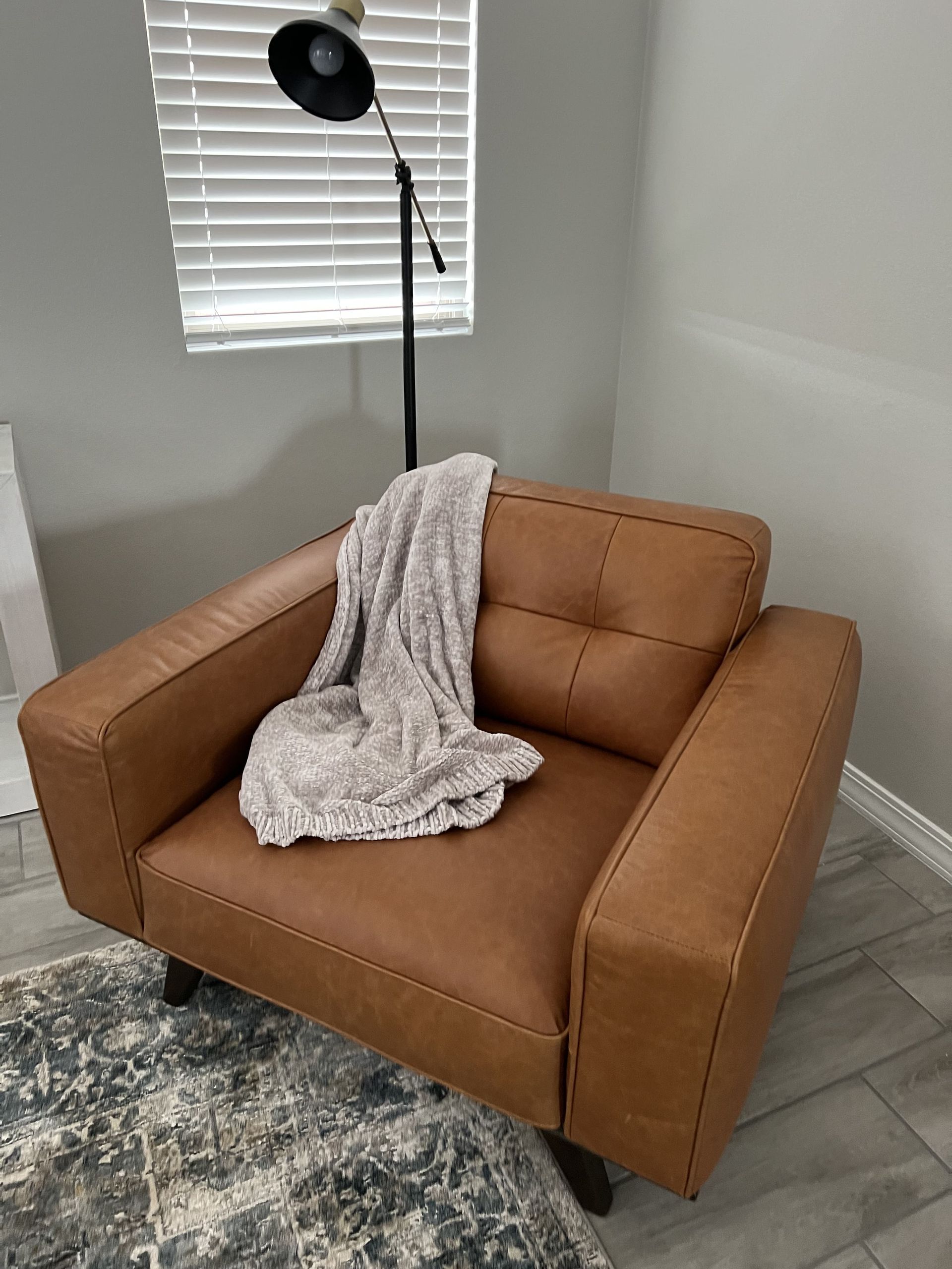 A brown leather chair with a blanket on it in a living room.