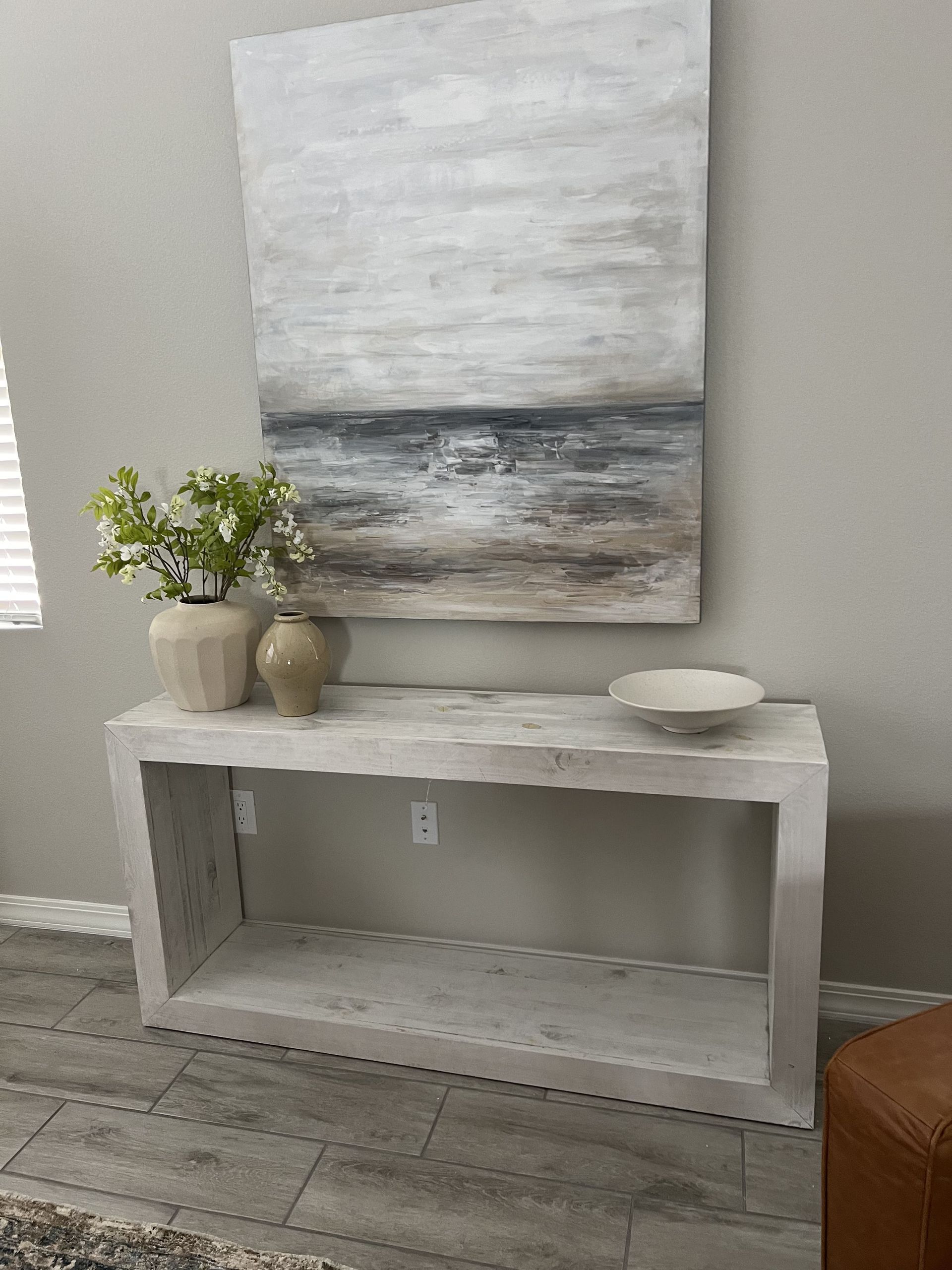 A living room with a table and a painting on the wall.