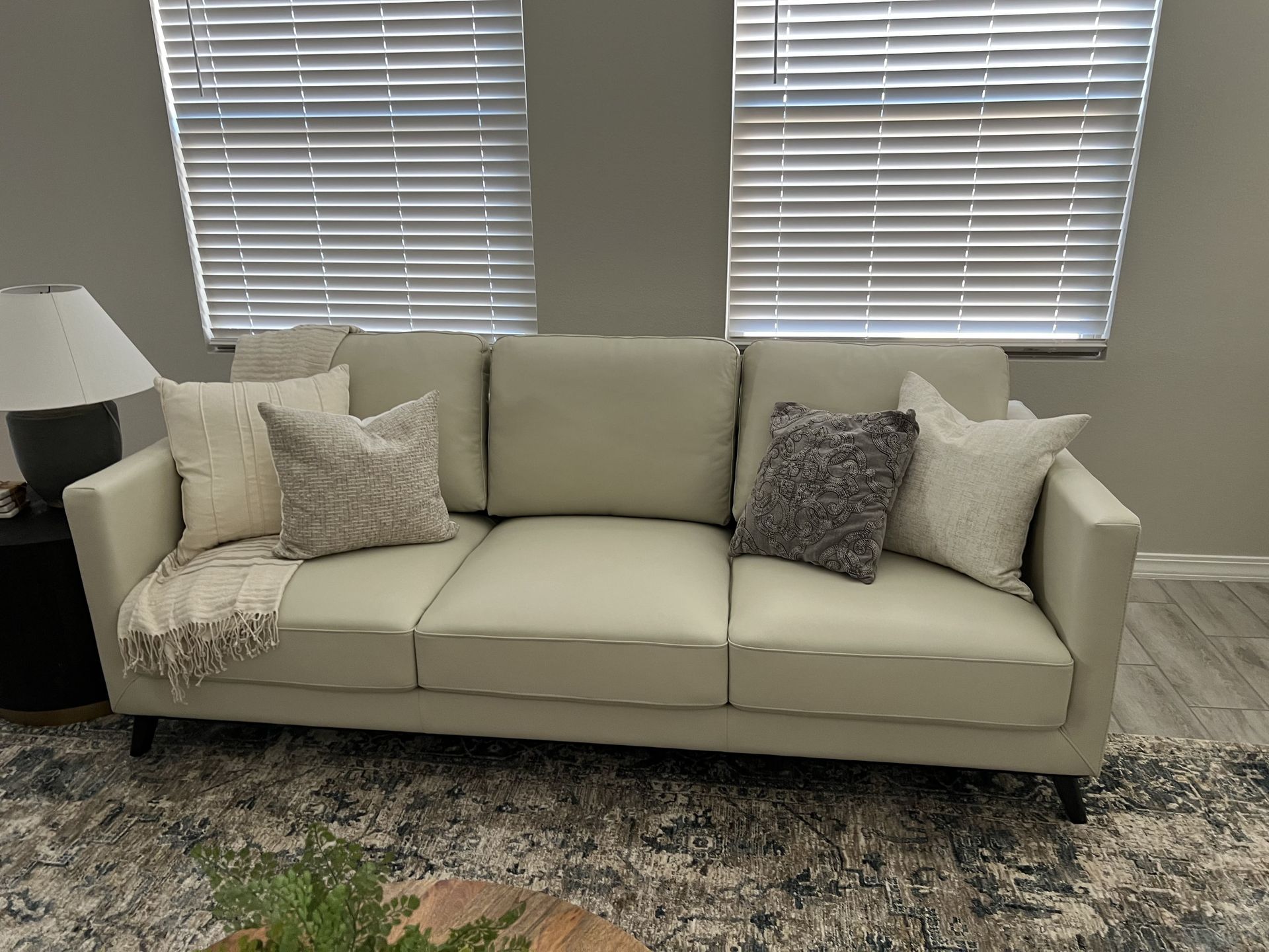 A white couch is sitting in a living room next to a window.
