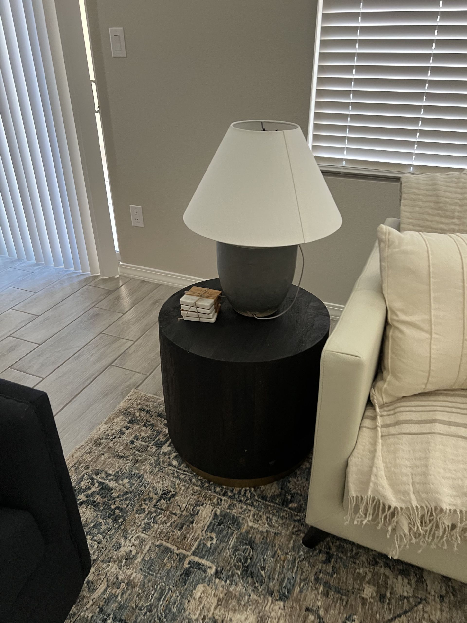 A lamp is sitting on a small table next to a chair in a living room.