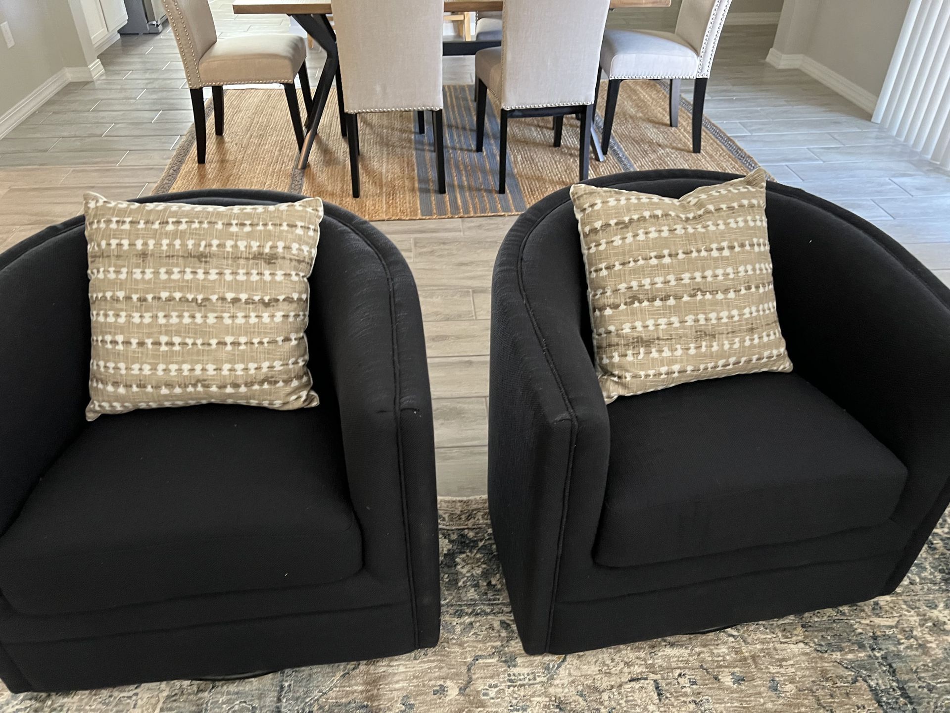 Two black chairs are sitting next to each other in a living room.