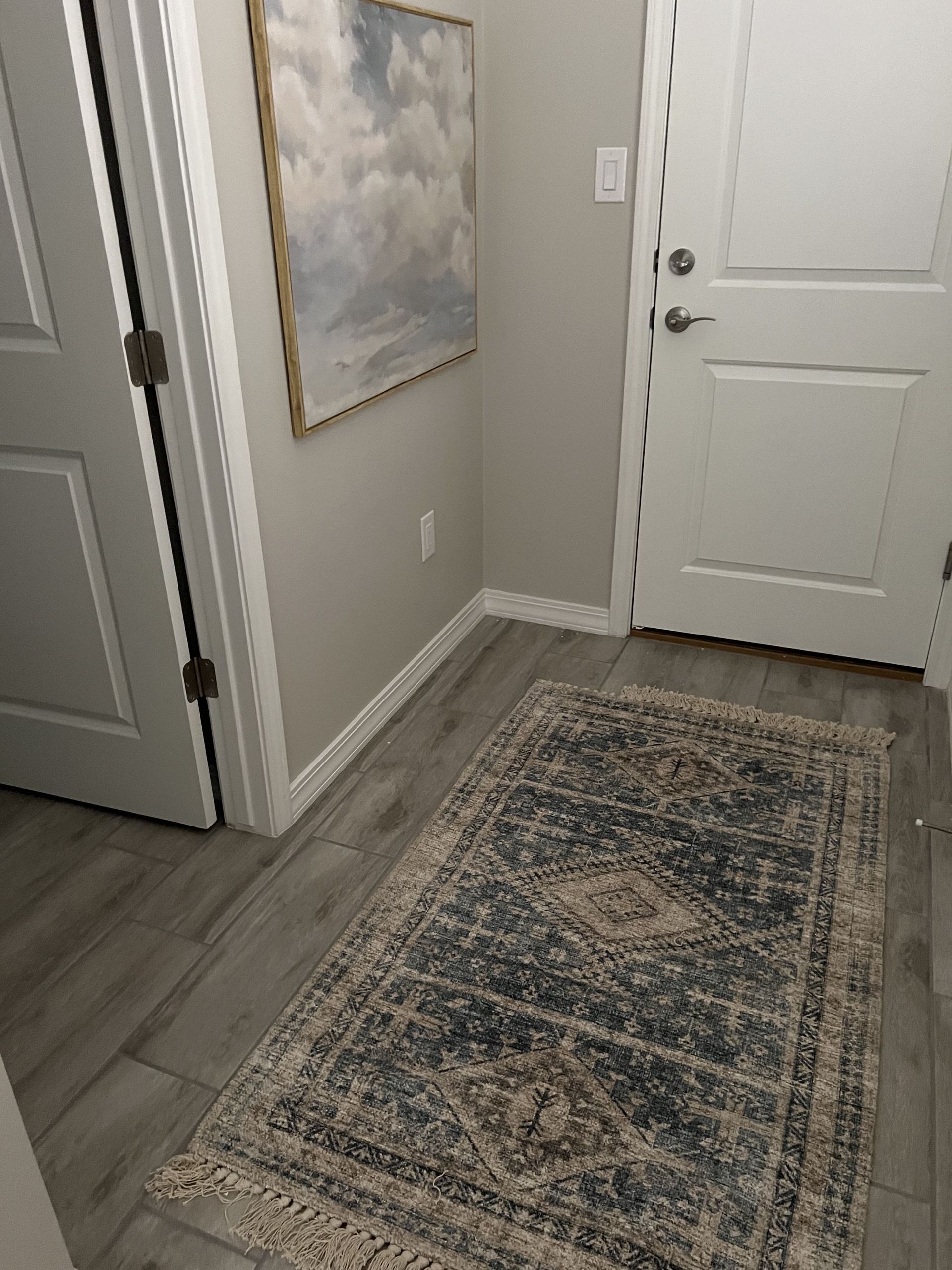 A hallway with a rug and a painting on the wall.