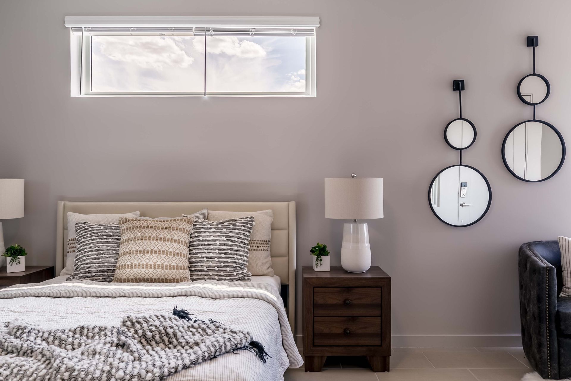 A bedroom with a bed , nightstand , lamps and a window.