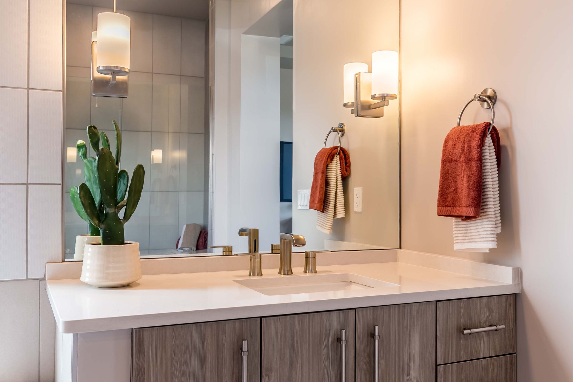 A bathroom with a sink , mirror and towels hanging on the wall.