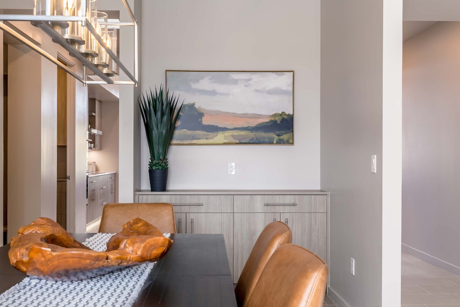 A dining room with a table and chairs and a painting on the wall.