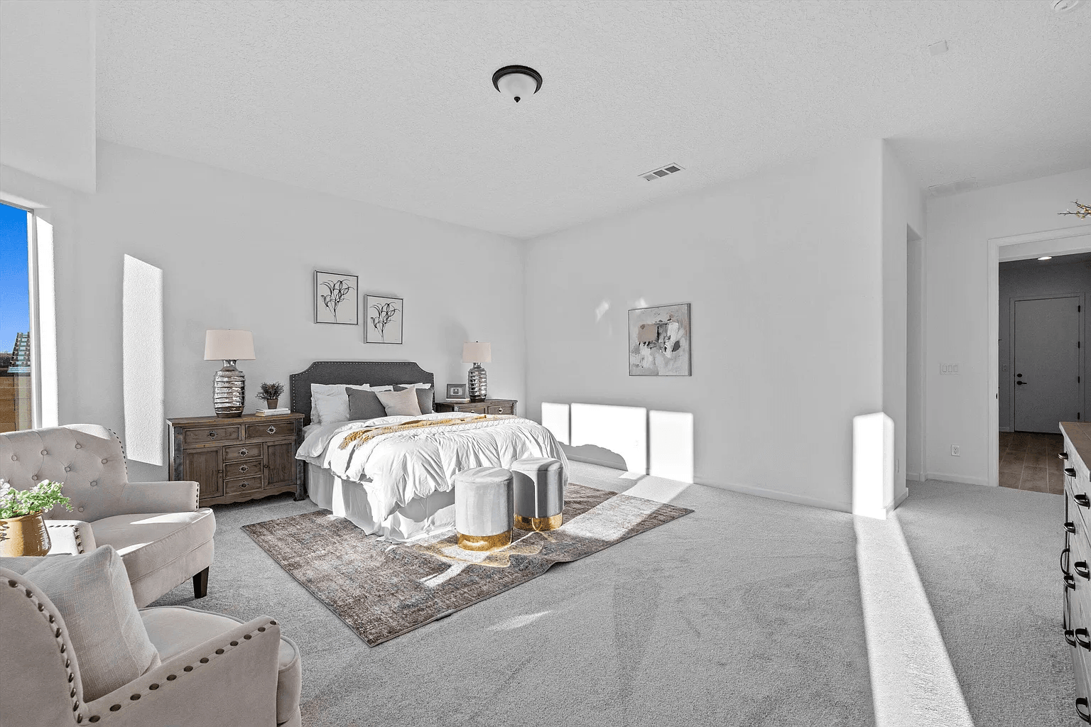 A bedroom with a bed , chair , dresser and rug.
