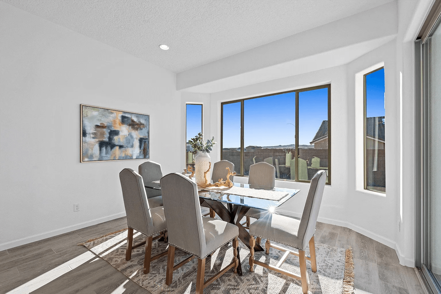 A dining room with a table and chairs and a large window.