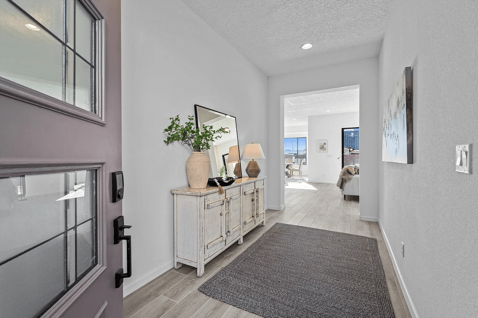 A hallway in a house with a purple door and a rug.