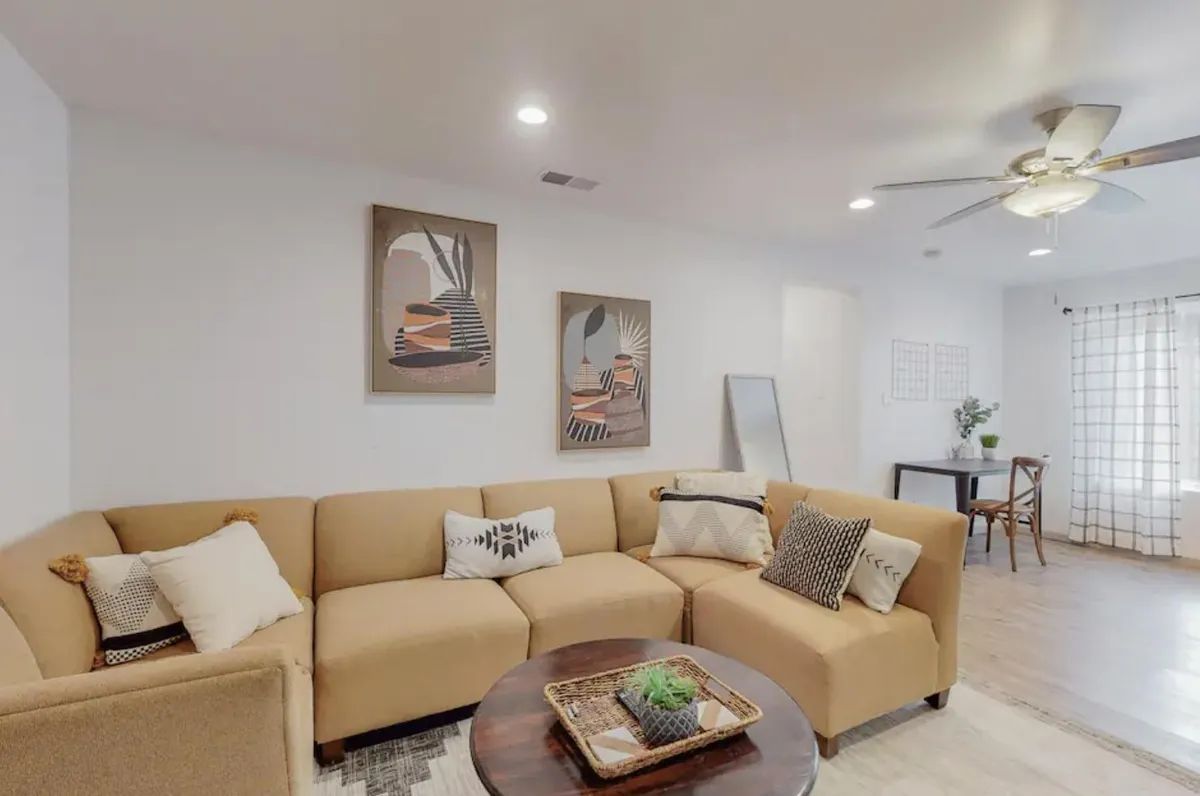 A living room with a large sectional couch and a ceiling fan.