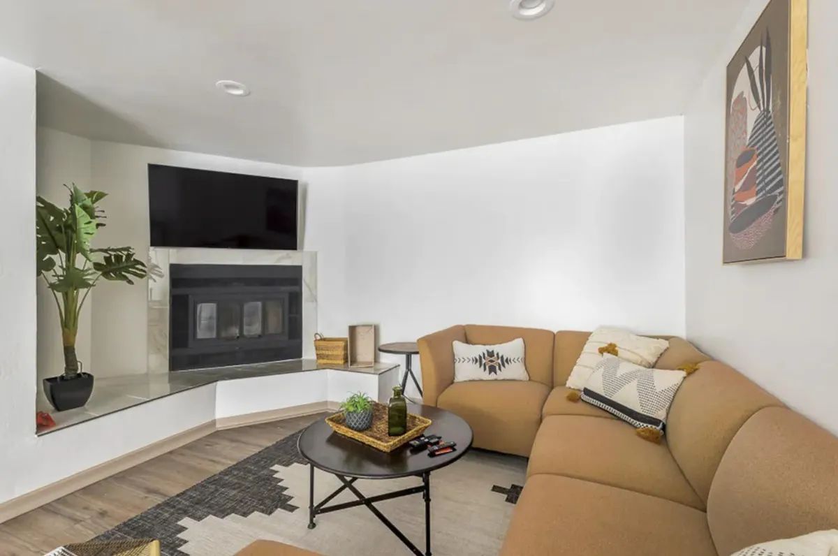 A living room with a couch , coffee table , television and fireplace.