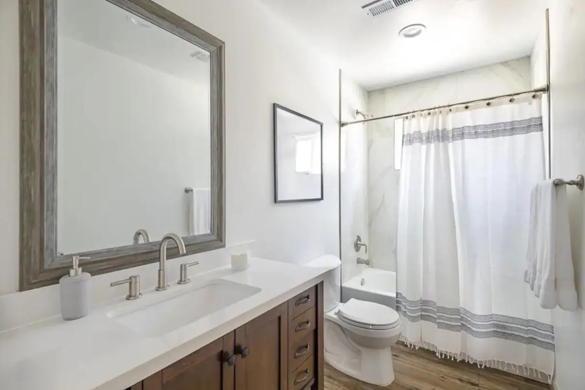 A bathroom with a sink , toilet , shower curtain and mirror.