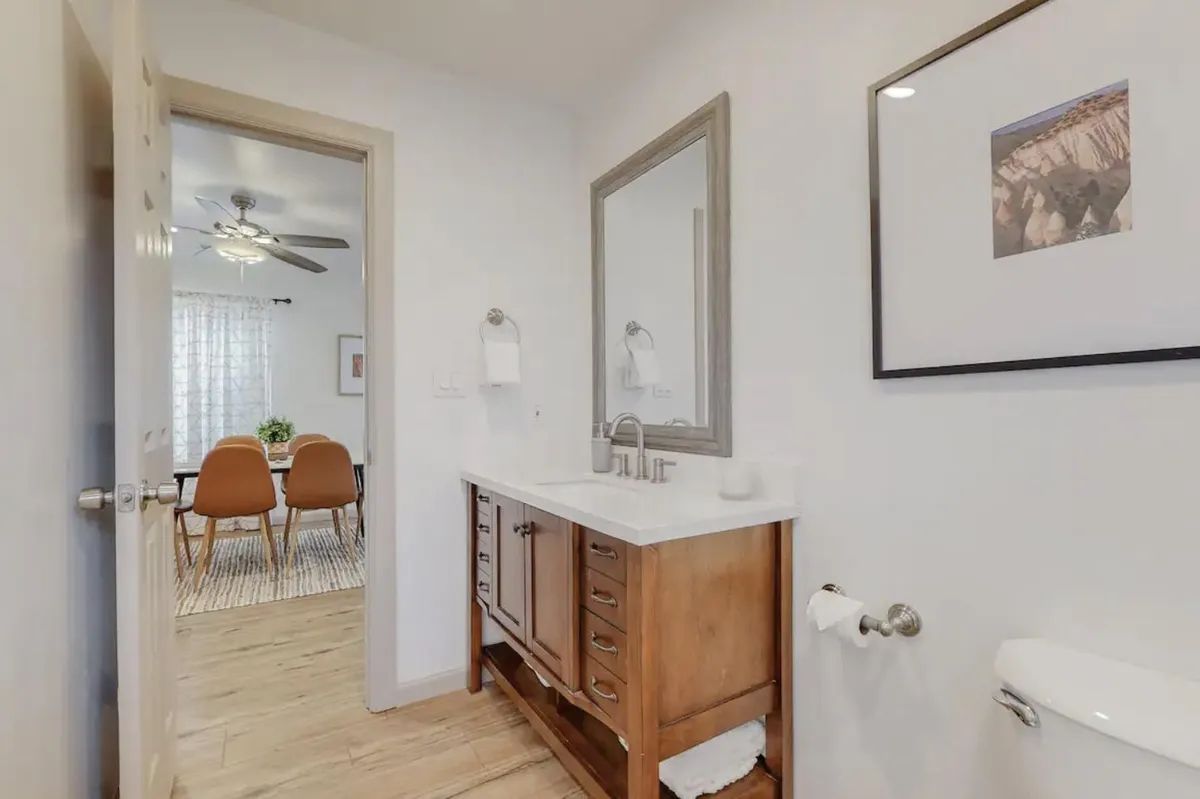 A bathroom with a sink , toilet , mirror and ceiling fan.