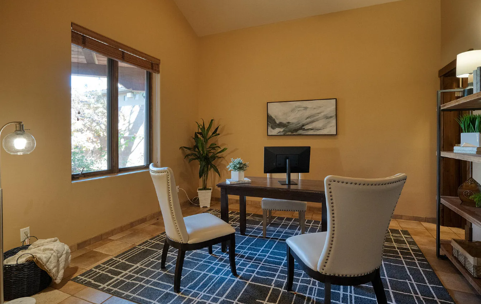A home office with two chairs , a desk and a computer.
