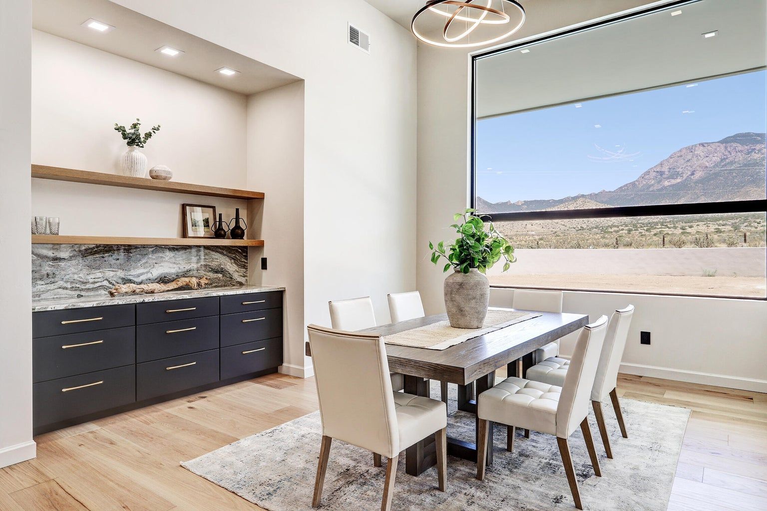 A dining room with a table and chairs and a large window.