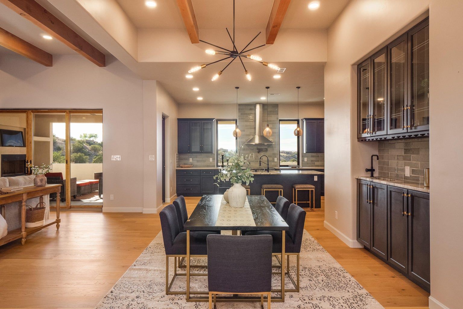 A dining room with a table and chairs and a kitchen in the background.