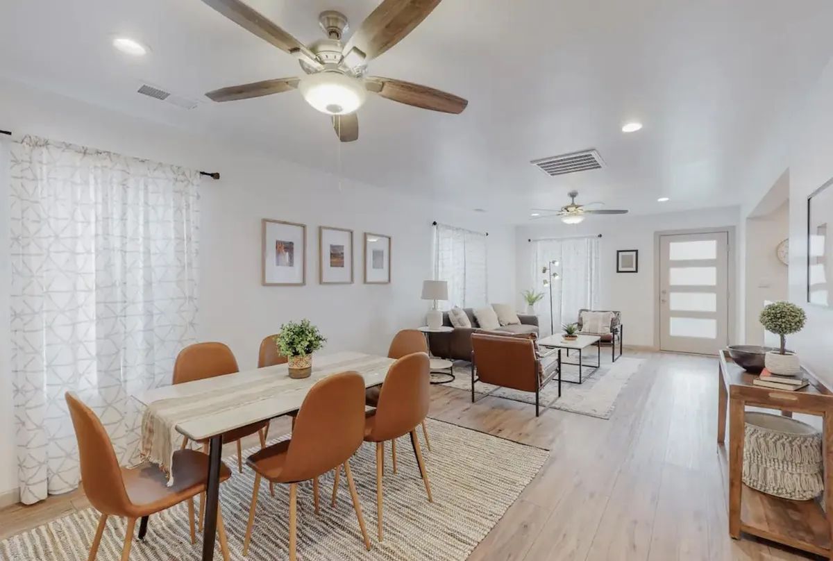 A living room with a table and chairs and a ceiling fan