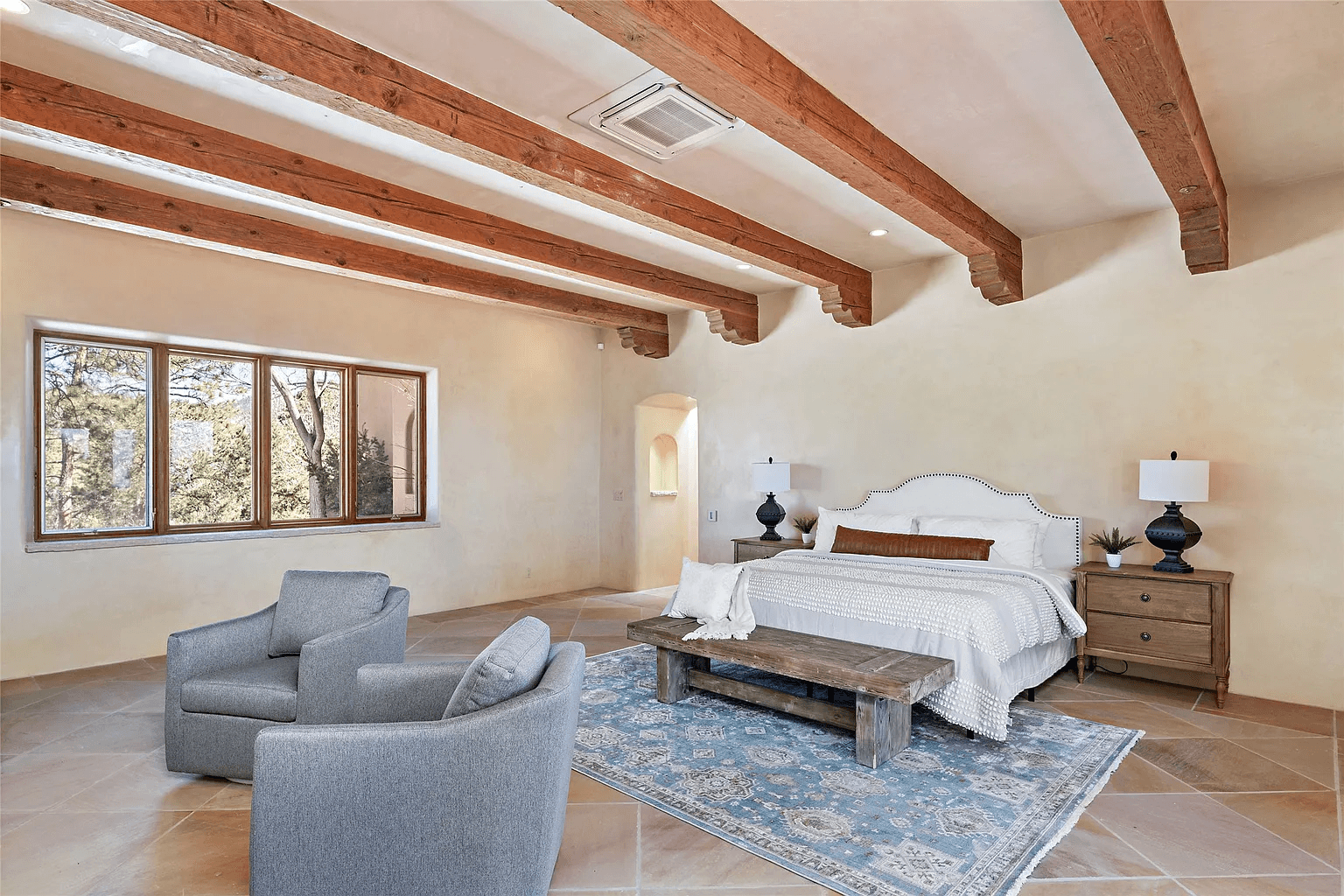 A bedroom with a large bed , two chairs , and a rug.