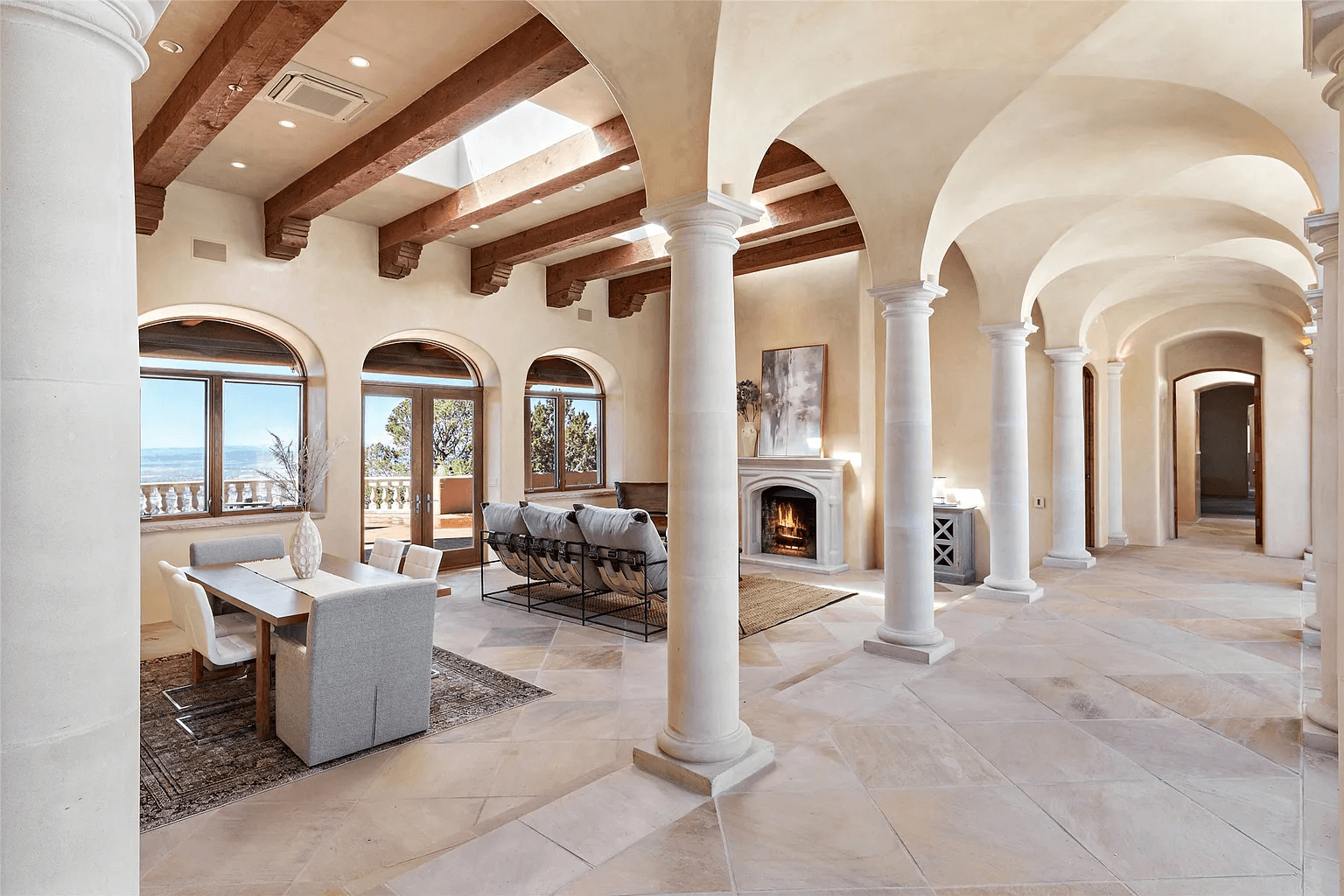 A living room with arched ceilings and columns and a fireplace.