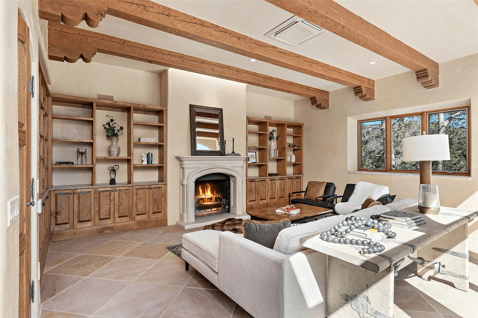 A living room with a fireplace , couch , chairs and shelves.