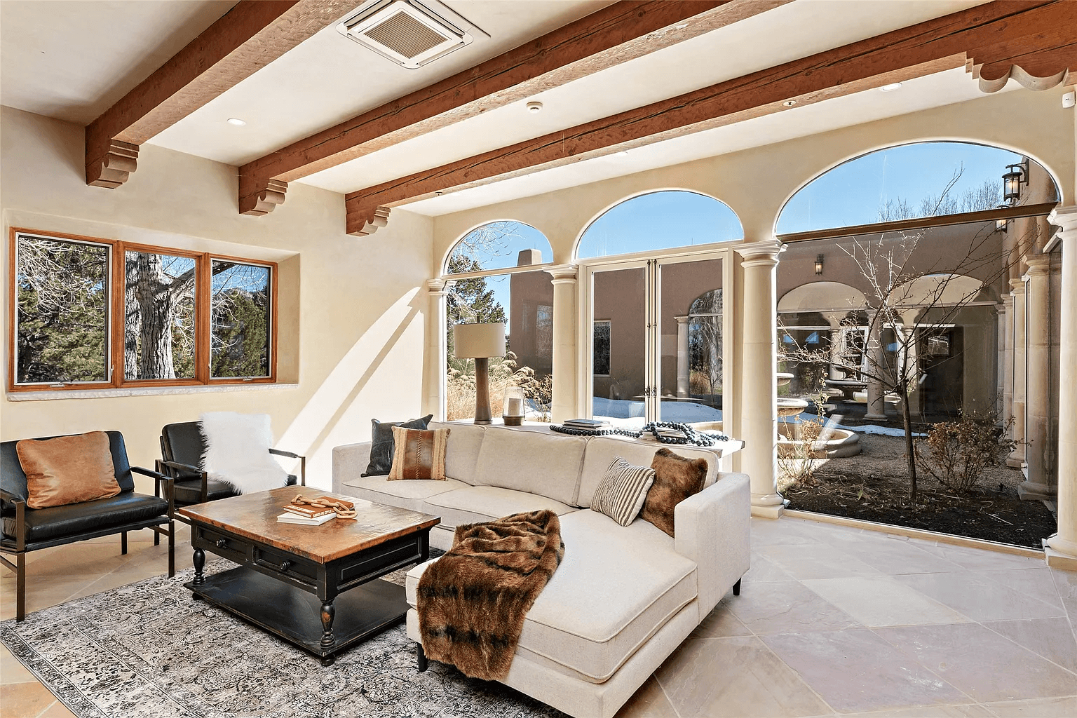 A living room with a couch , coffee table , chairs and arched windows.