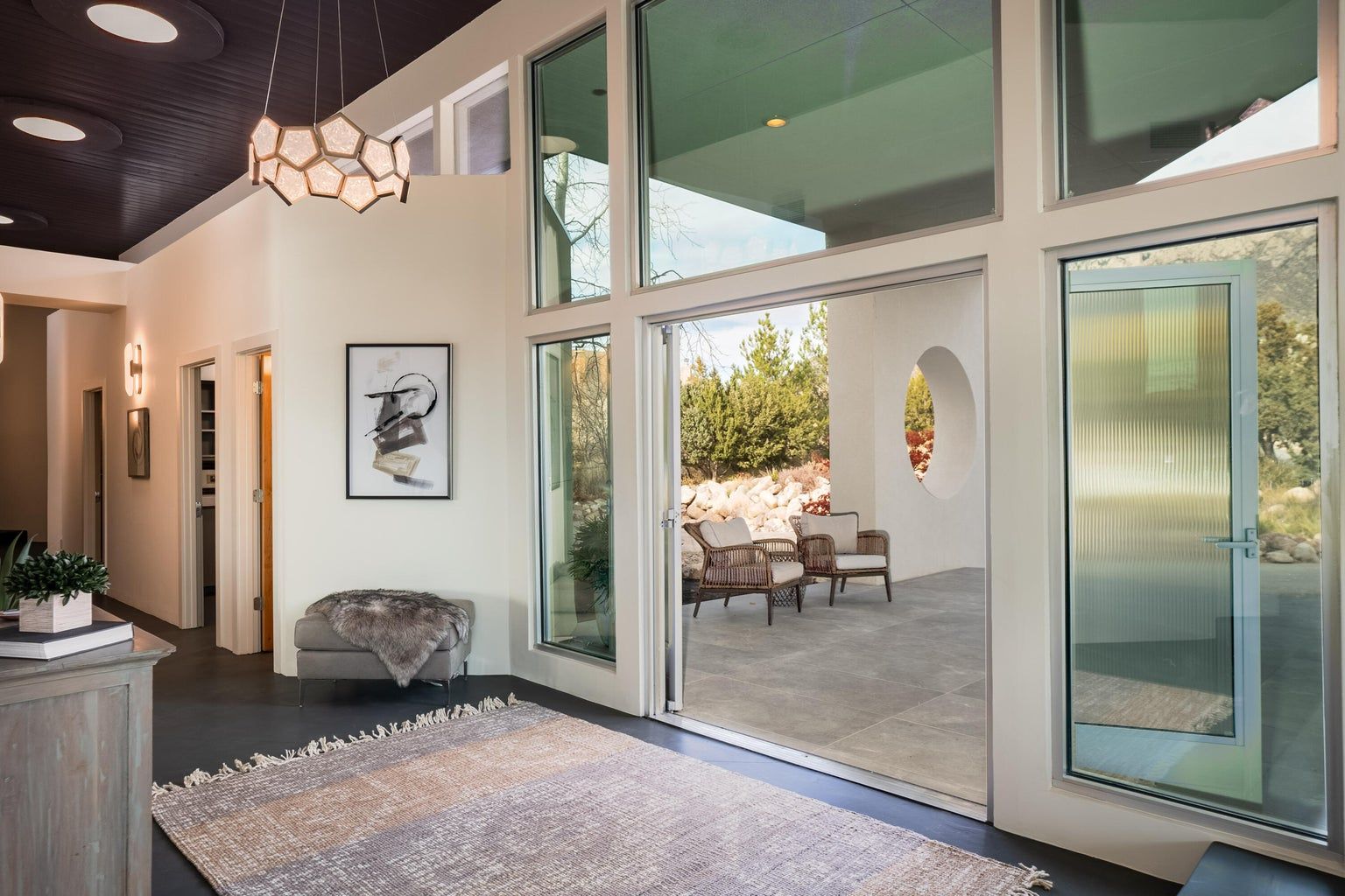 A living room with a lot of windows and a rug.