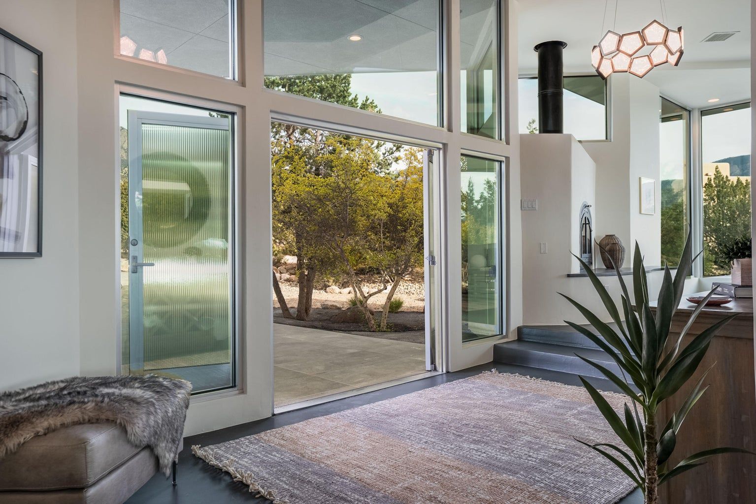 A living room with a lot of windows and a rug.