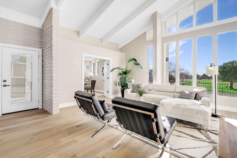 A living room with a couch , chairs , and a lot of windows.