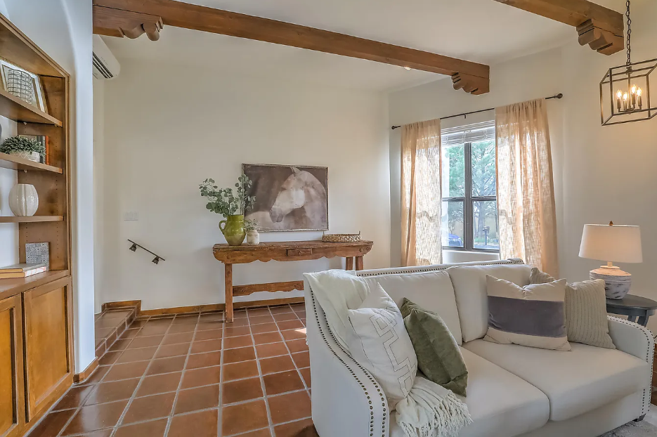 A living room with a white couch and a painting on the wall.