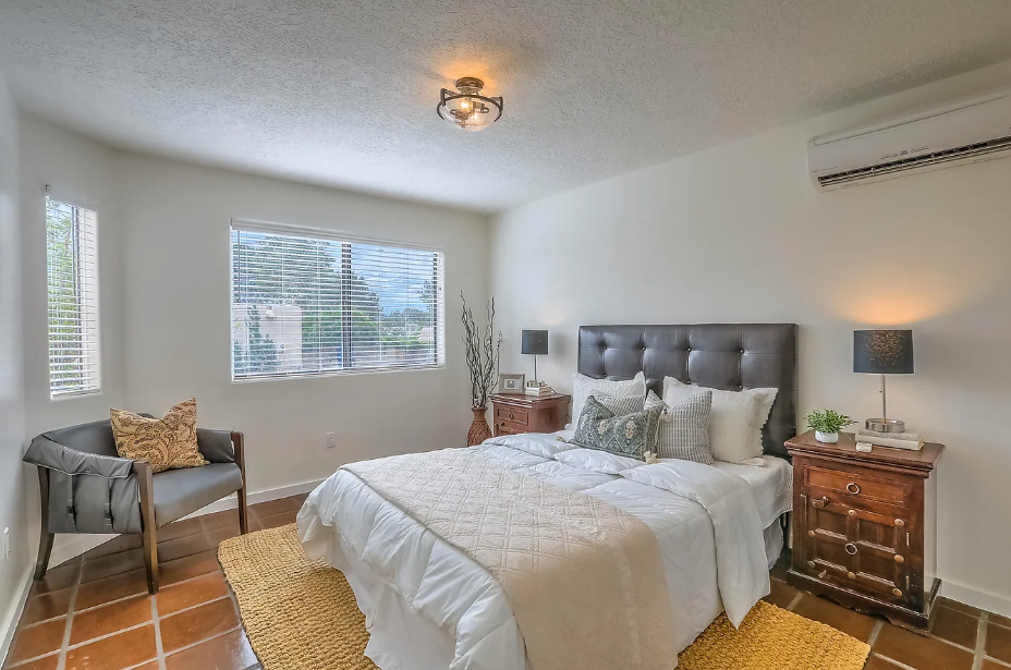 A bedroom with a bed , nightstand , chair and window.
