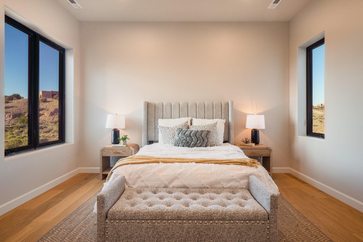 There is a large bed in the middle of the room with two windows.