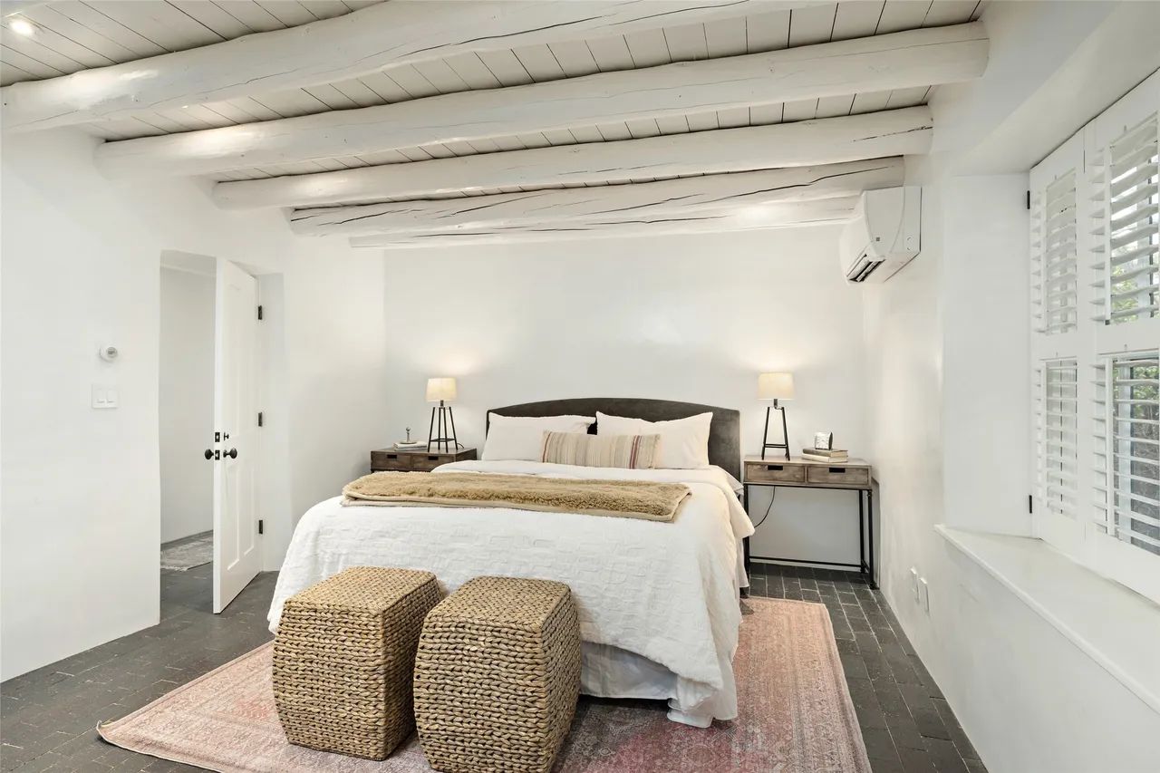A bedroom with a bed and two wicker ottomans