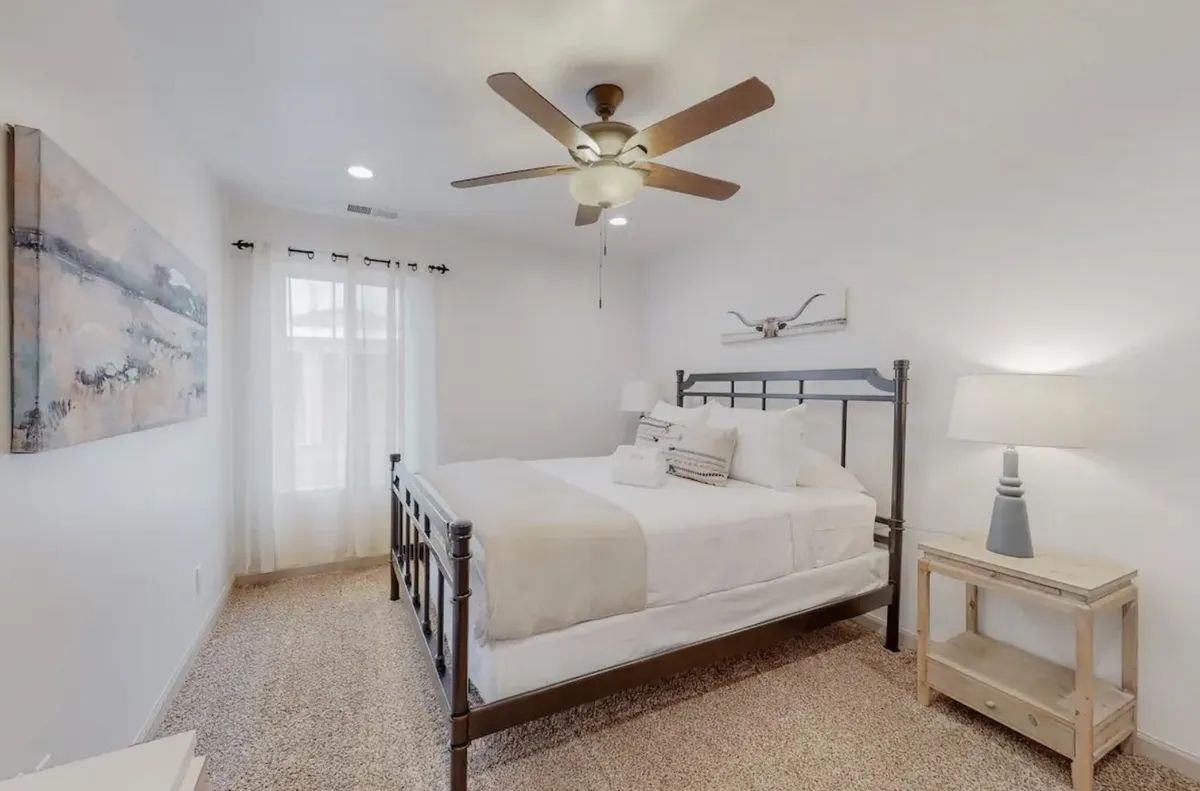 A bedroom with a bed , nightstand , lamp and ceiling fan.