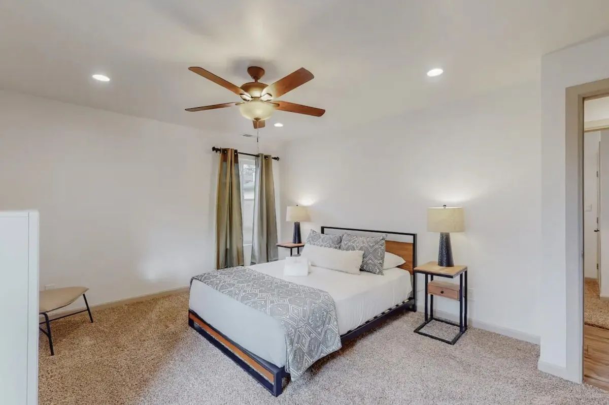 A bedroom with a bed and a ceiling fan.