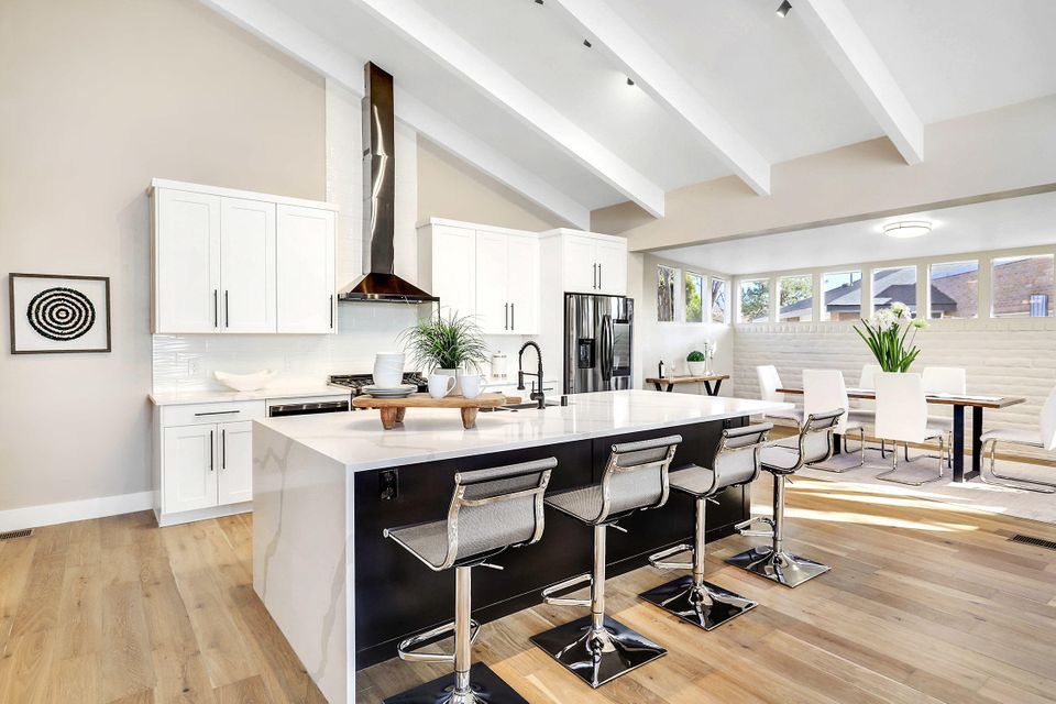A kitchen with a large island and stools in a house.