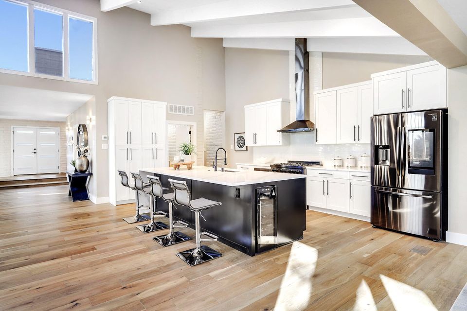 A kitchen with white cabinets , stainless steel appliances , and a large island.