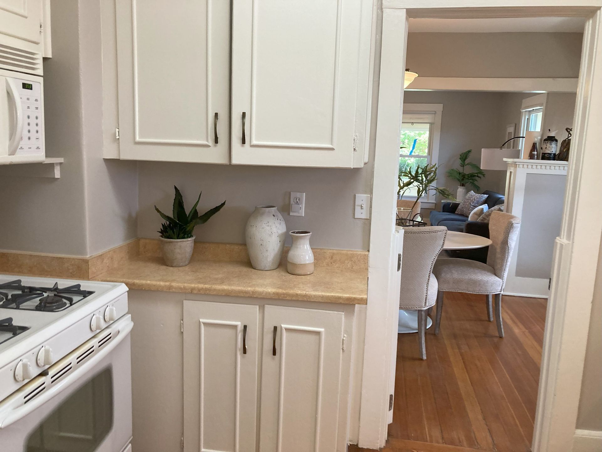 A kitchen with white cabinets and a stove and microwave