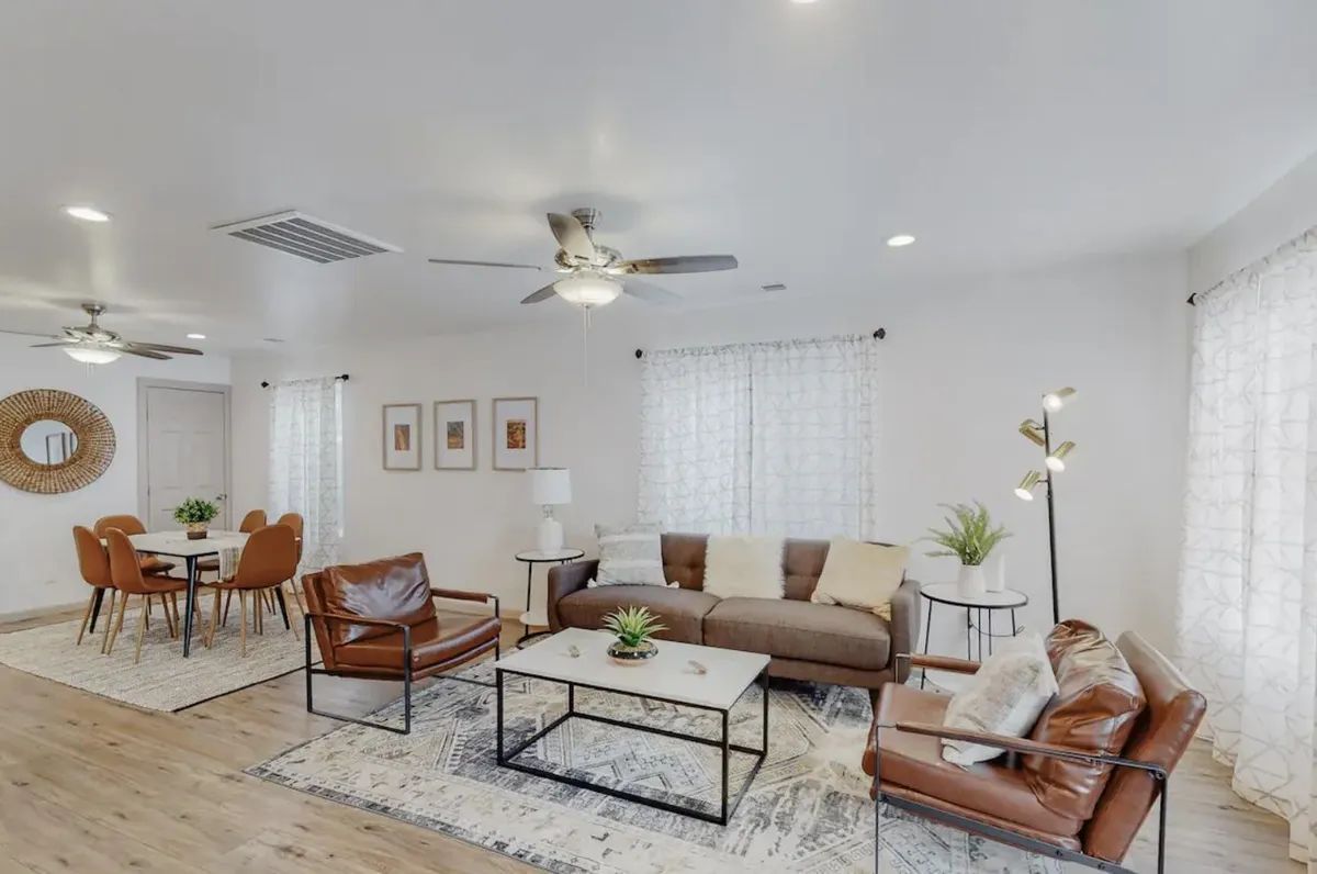 A living room with a couch , chairs , coffee table and ceiling fan.
