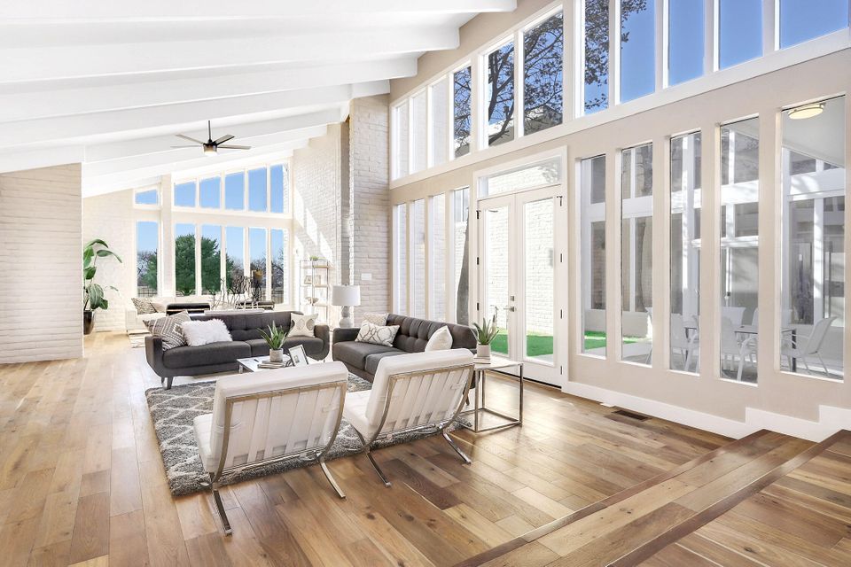 A living room with a lot of windows and hardwood floors.
