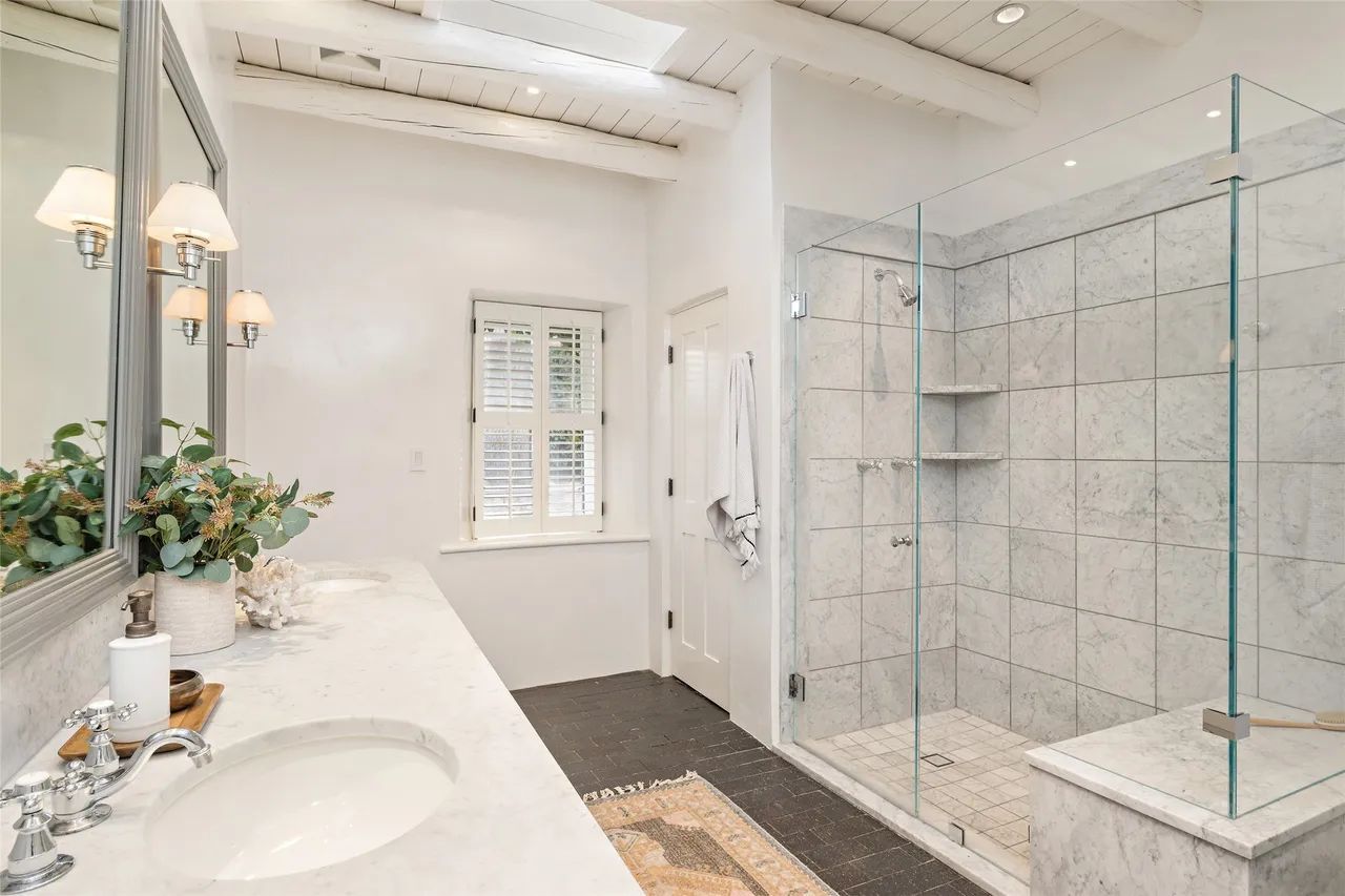 A bathroom with a walk in shower , sink and mirror.