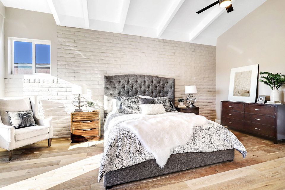 A bedroom with a bed , chair , dresser and ceiling fan.